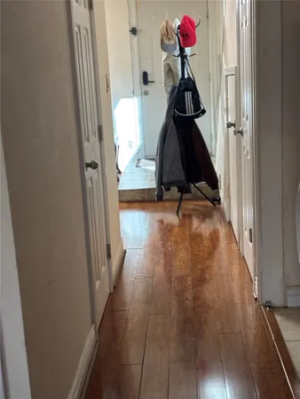 a view of a hallway with wooden floor and cabinet