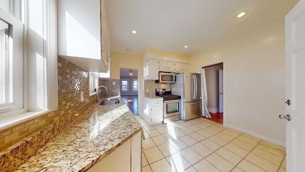 17 Gorham Road, Unit 2 Medford, MA 02155 - Photo 14 of 37 a view of a kitchen with kitchen island granite countertop a refrigerator cabinets and wooden floor