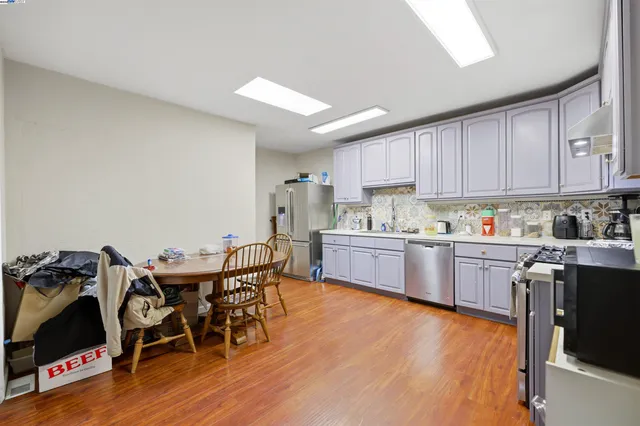 a kitchen with granite countertop stainless steel appliances a sink cabinets and wooden floor