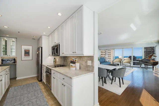 a kitchen with stainless steel appliances granite countertop a stove top oven a sink a dining table and chairs with wooden floor