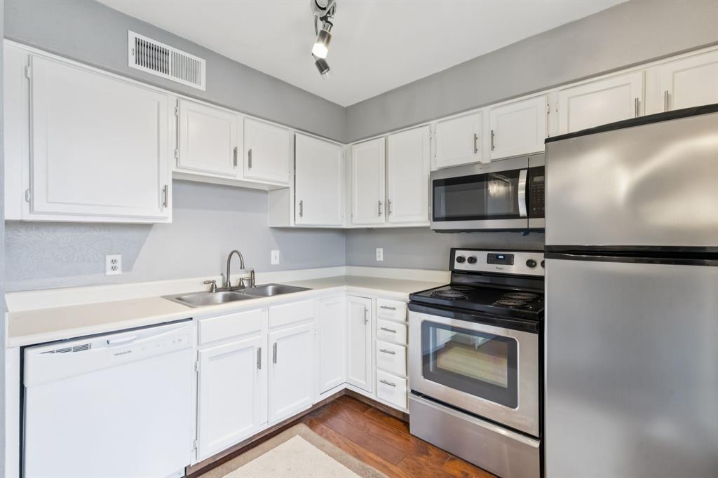 4748 Old Bent Tree Lane, Unit 1808 Dallas, TX 75287 - Photo 5 of 28 a kitchen with cabinets stainless steel appliances and wooden floor