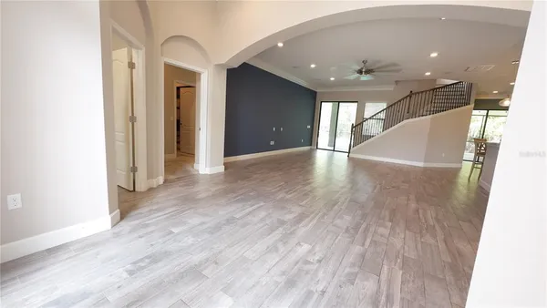 a view of an empty room with wooden floor and a bathroom