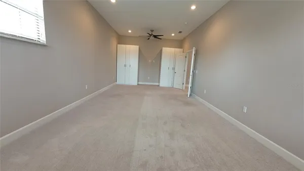 en empty room with windows and ceiling fan