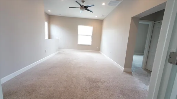 an empty room with a ceiling fan and a rug