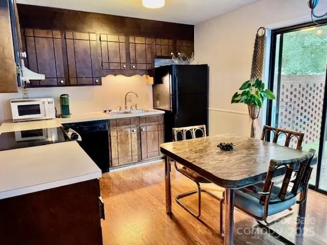 a kitchen with stainless steel appliances granite countertop a stove a refrigerator a sink a dining table and chairs with wooden floor