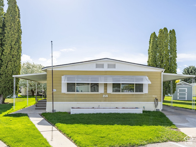 482 West 680 North Logan, UT 84321 - Photo 1 of 1 Manufactured / mobile home featuring a front lawn, a carport, a storage unit, and concrete driveway