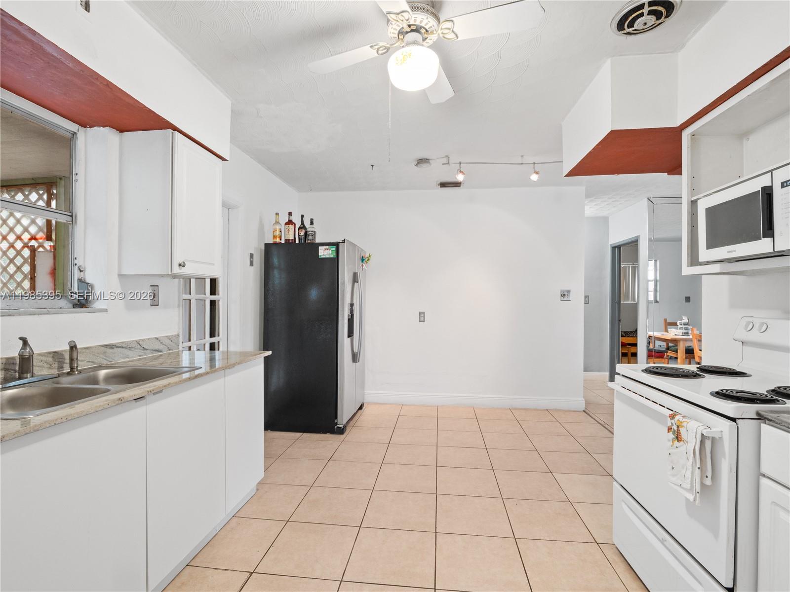 6111 Southwest 20th Court Miramar, FL 33023 - Photo 7 of 31 a kitchen with a sink a refrigerator and cabinets