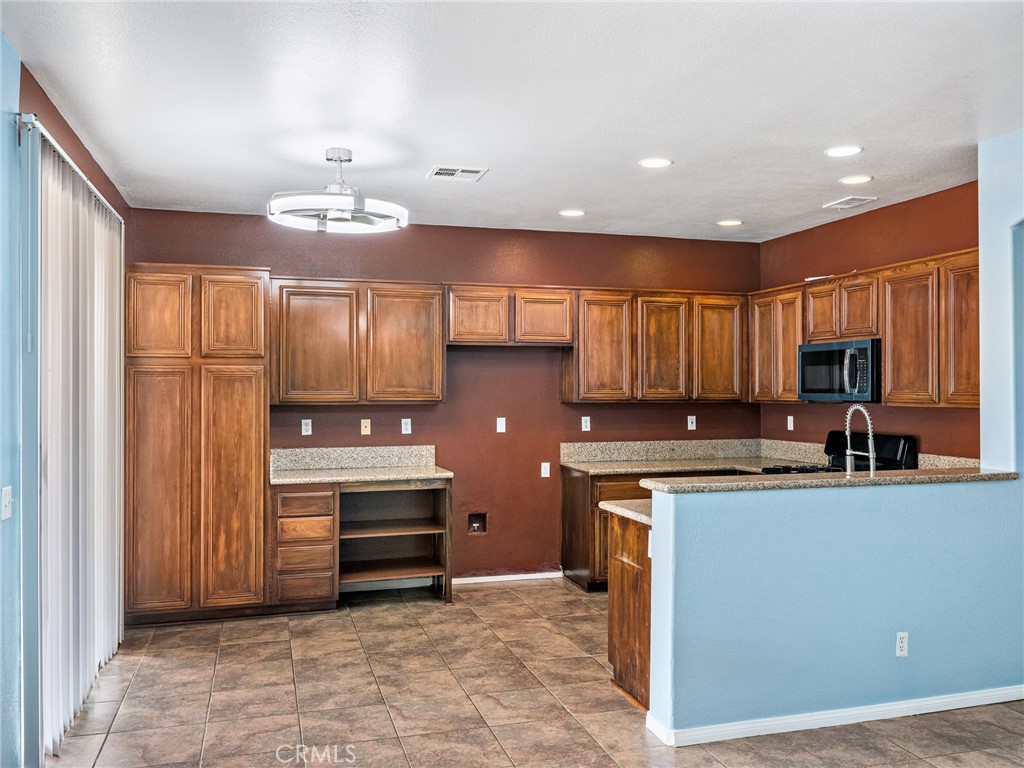 14400 Jeremiah Street Adelanto, CA 92301 - Photo 13 of 45 a kitchen with kitchen island granite countertop a sink counter top space appliances and cabinets