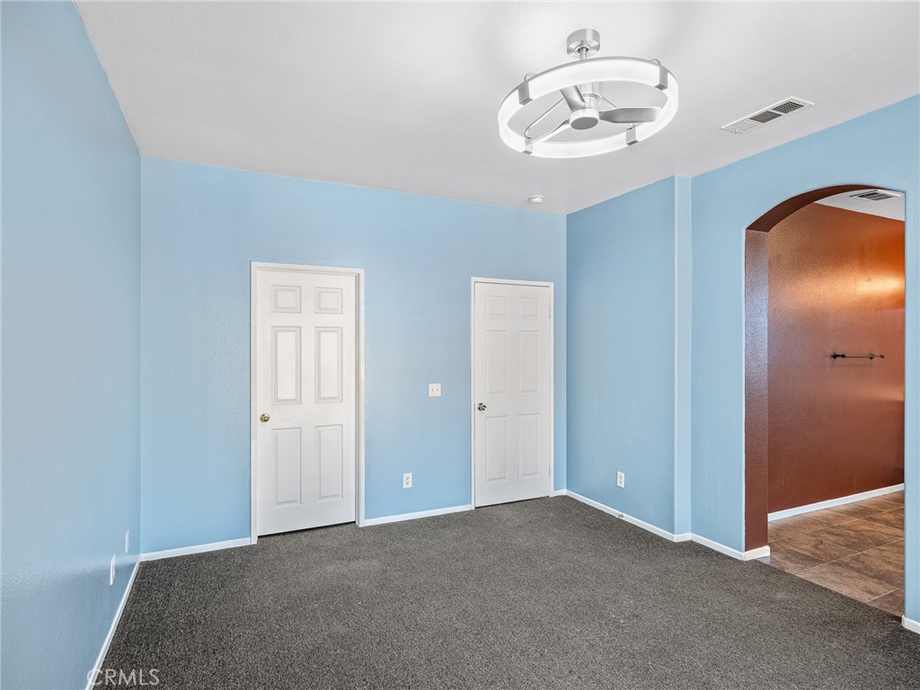 14400 Jeremiah Street Adelanto, CA 92301 - Photo 27 of 45 an empty room with a chandelier fan and wooden floor