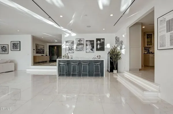 a living room with stainless steel appliances kitchen island granite countertop a refrigerator and cabinets