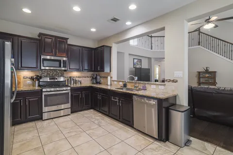 a kitchen with stainless steel appliances granite countertop a stove top oven a sink dishwasher and a refrigerator