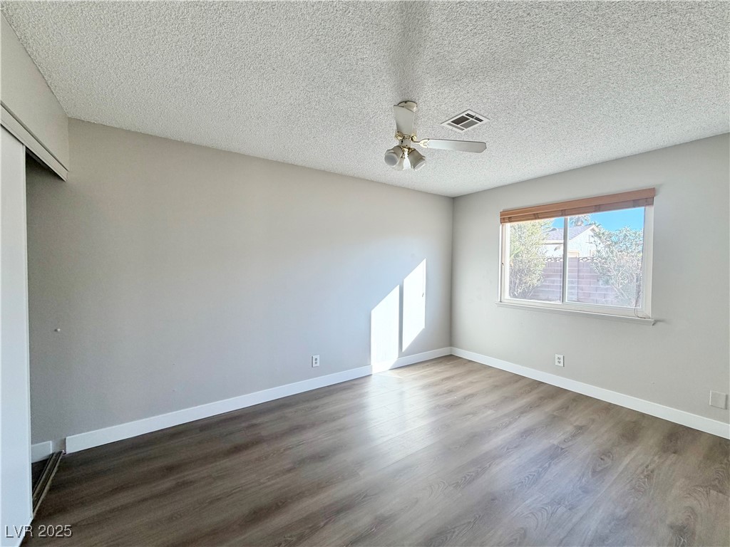 6401 Waterthrush Way Las Vegas, NV 89103 - Photo 11 of 19 Empty room featuring dark wood-type flooring, a textured ceiling, and a ceiling fan