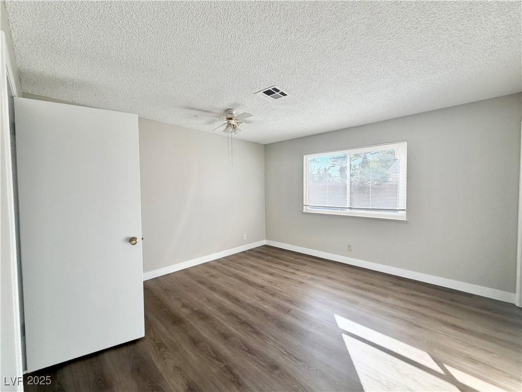6401 Waterthrush Way Las Vegas, NV 89103 - Photo 13 of 19 Unfurnished room featuring wood finished floors, a textured ceiling, and ceiling fan