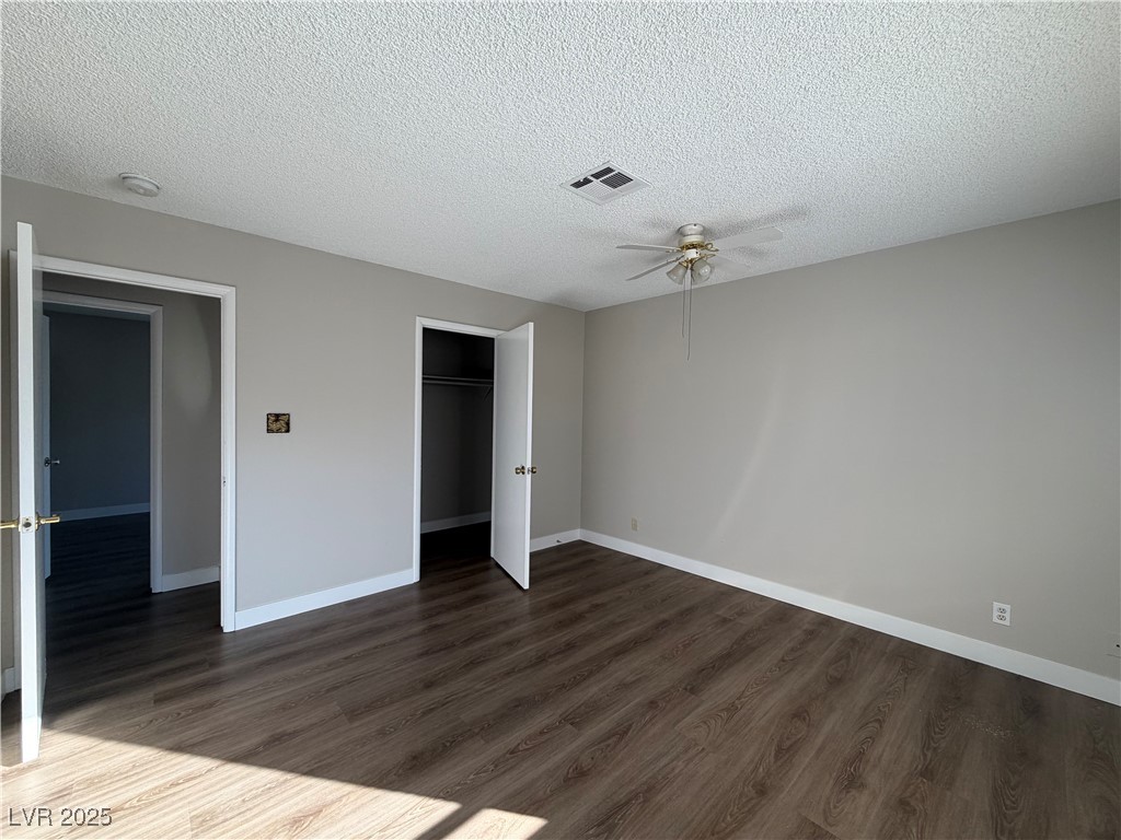 6401 Waterthrush Way Las Vegas, NV 89103 - Photo 14 of 19 Unfurnished bedroom featuring dark wood-type flooring, a textured ceiling, a closet, and a ceiling fan
