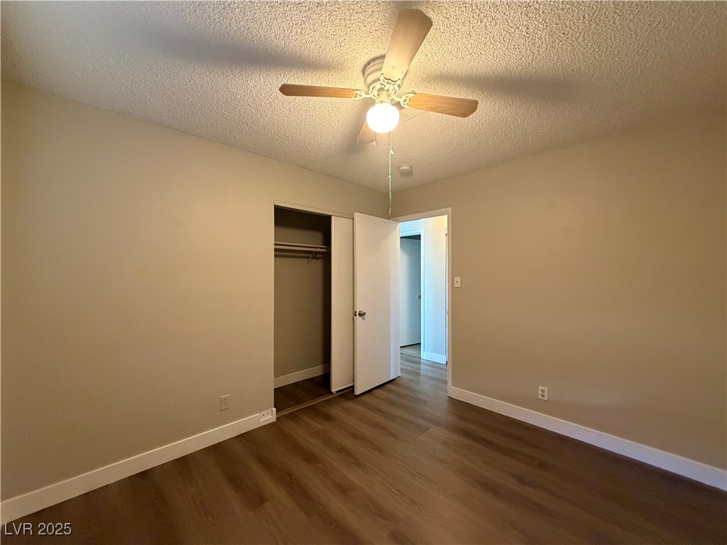 6401 Waterthrush Way Las Vegas, NV 89103 - Photo 18 of 19 Unfurnished bedroom featuring a textured ceiling, dark wood finished floors, a ceiling fan, and a closet