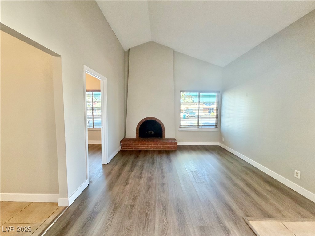 6401 Waterthrush Way Las Vegas, NV 89103 - Photo 4 of 19 Unfurnished living room with plenty of natural light, light wood-style floors, a fireplace, and high vaulted ceiling