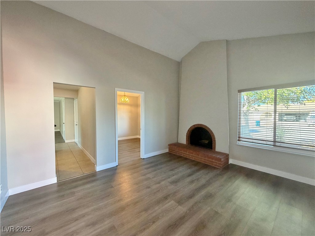 6401 Waterthrush Way Las Vegas, NV 89103 - Photo 5 of 19 Unfurnished living room with a fireplace, dark wood finished floors, and high vaulted ceiling
