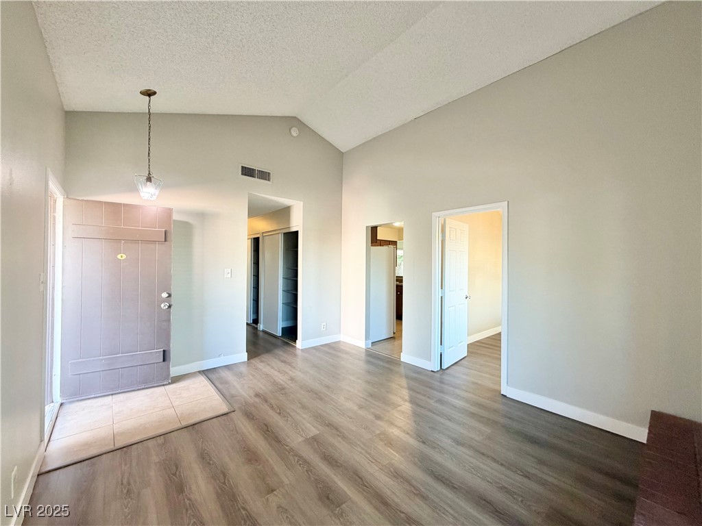 6401 Waterthrush Way Las Vegas, NV 89103 - Photo 6 of 19 Unfurnished living room with light wood-style floors, high vaulted ceiling, and a textured ceiling