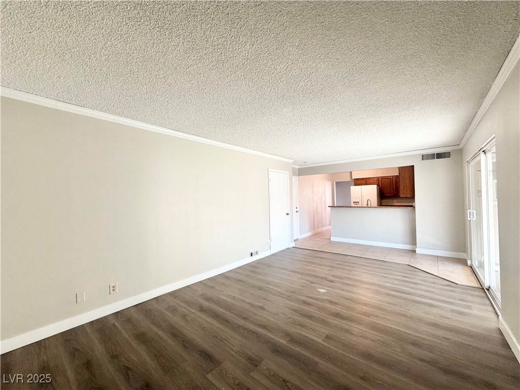 6401 Waterthrush Way Las Vegas, NV 89103 - Photo 8 of 19 Unfurnished living room with crown molding, light wood-style flooring, and a textured ceiling