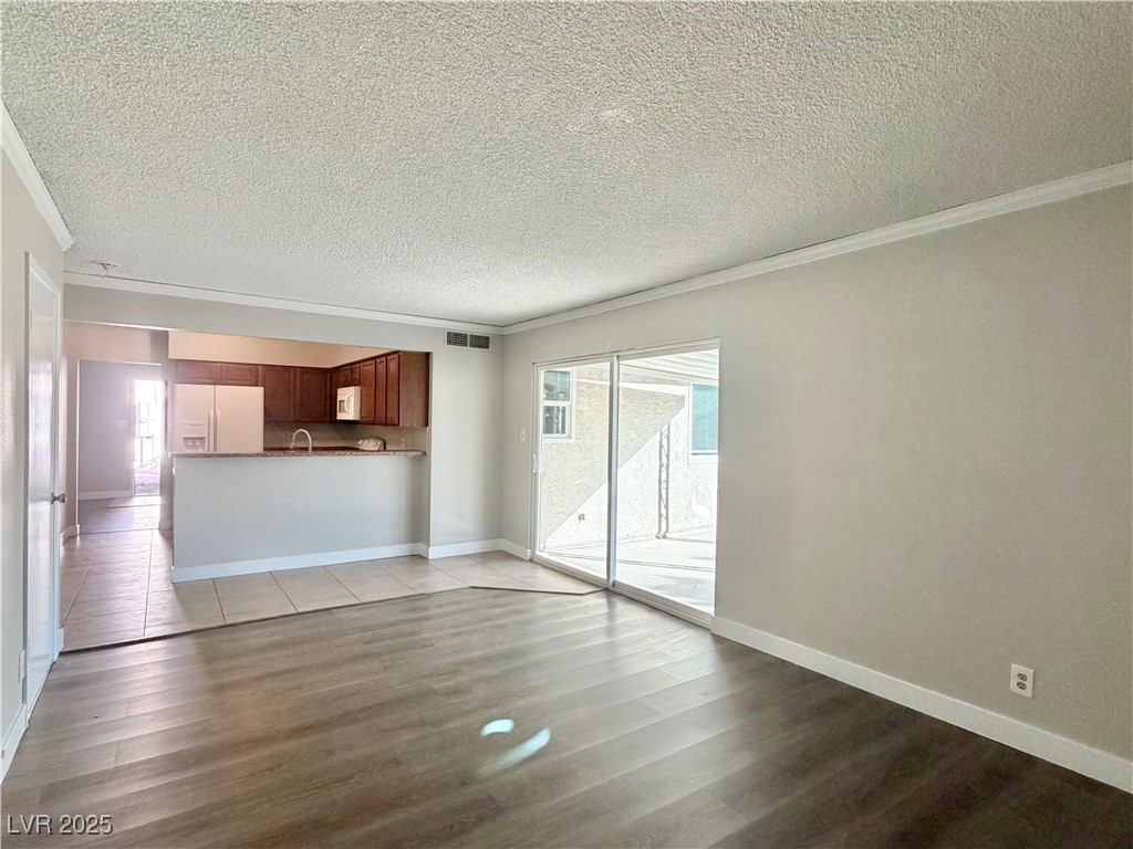 6401 Waterthrush Way Las Vegas, NV 89103 - Photo 9 of 19 Unfurnished living room featuring crown molding, light wood-style flooring, and a textured ceiling