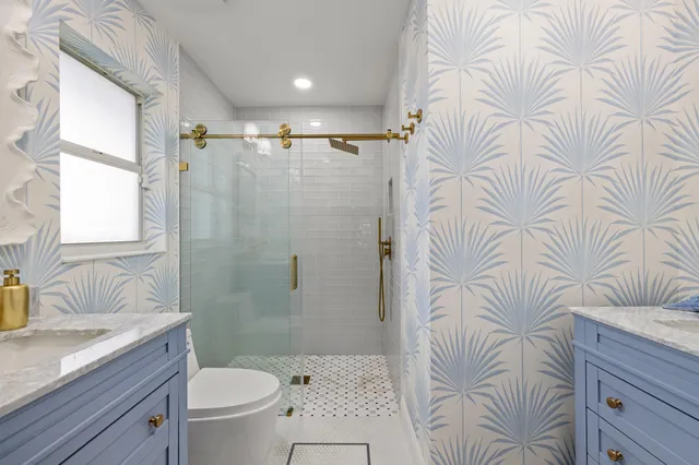 a bathroom with a granite countertop bathtub sink vanity mirror and toilet
