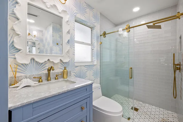 a bathroom with a granite countertop sink a toilet and shower