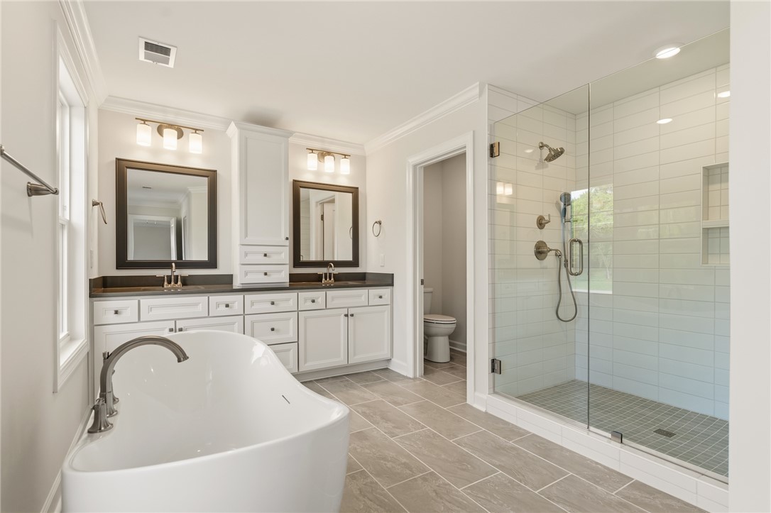 1108 Manse Jolly Road Anderson, SC 29621 - Photo 25 of 45 This primary bathroom features a standalone tub, double vanity, and spacious glass-enclosed shower.
