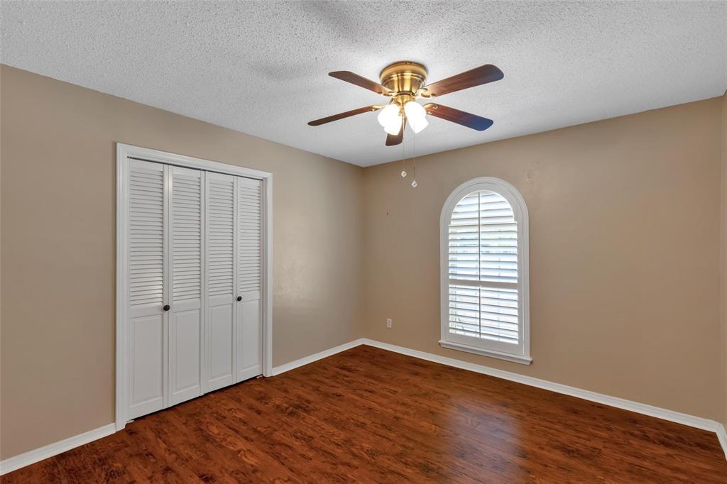 625 Deer Drive Greenville, TX 75402 - Photo 15 of 29 an empty room with wooden floor chandelier fan and windows