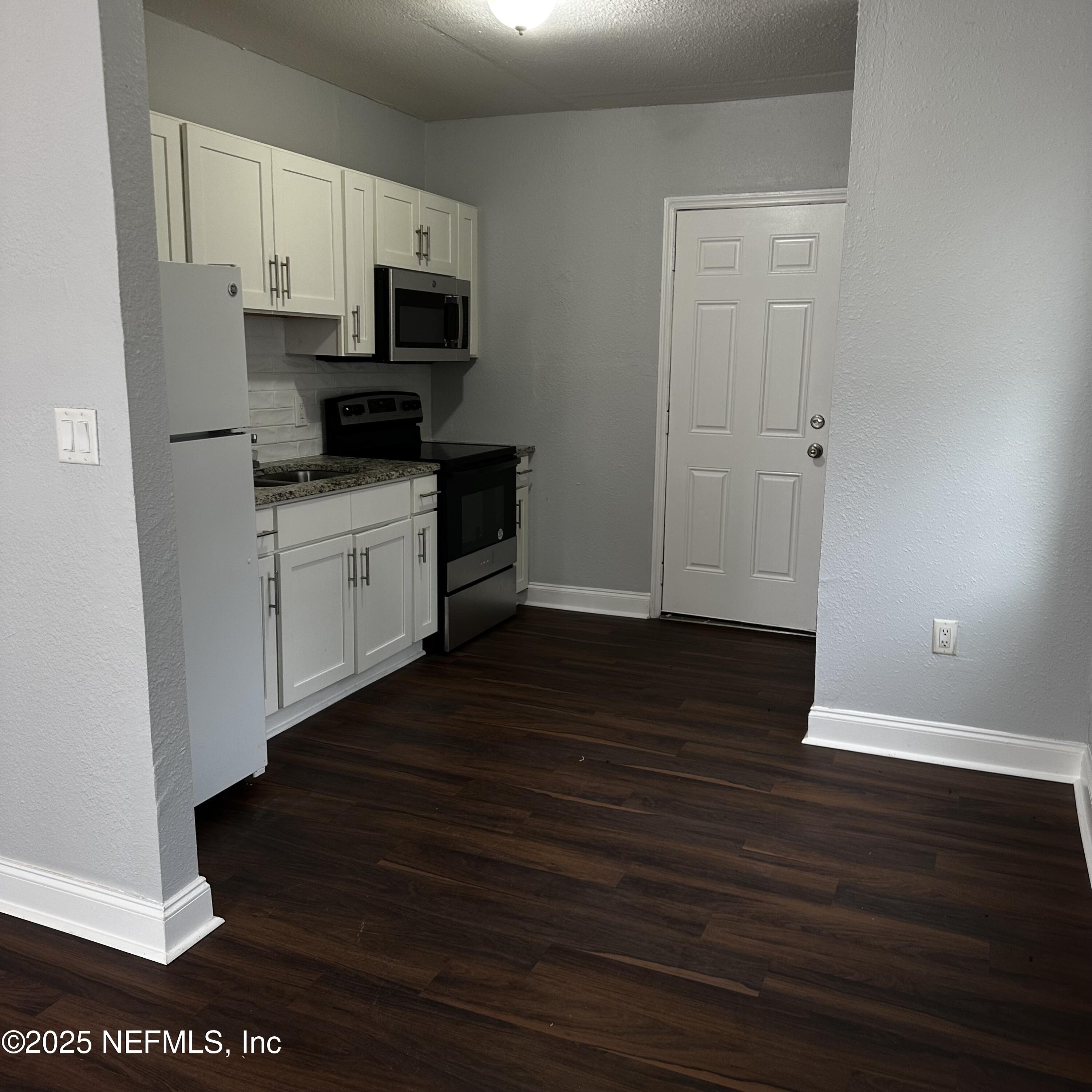 3615 Charles Street Jacksonville, FL 32209 - Photo 3 of 13 a kitchen with wooden floors and black appliances