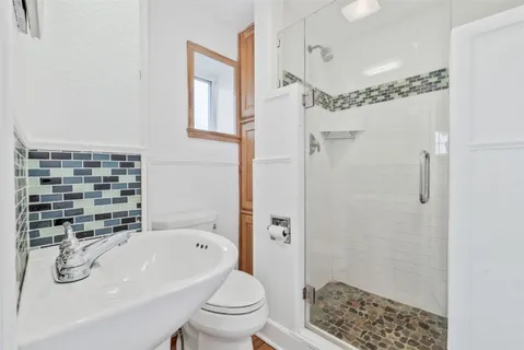 a bathroom with a granite countertop sink a toilet and shower
