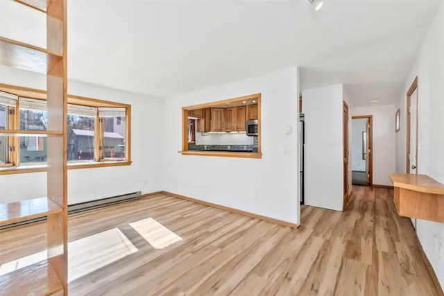 a view of an empty room with window and wooden floor