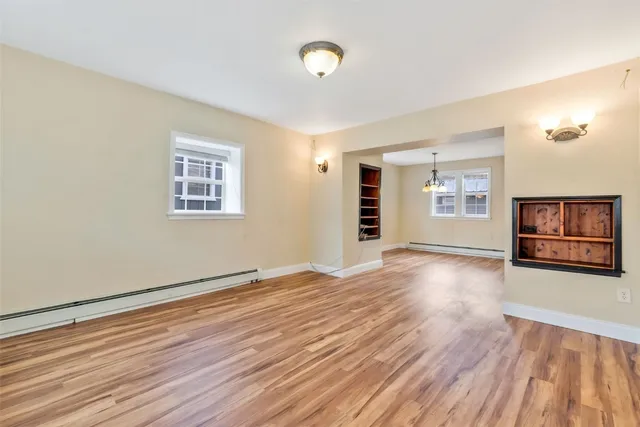 a view of an empty room with window and wooden floor