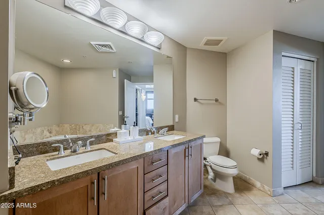 a bathroom with a double vanity sink toilet and a mirror