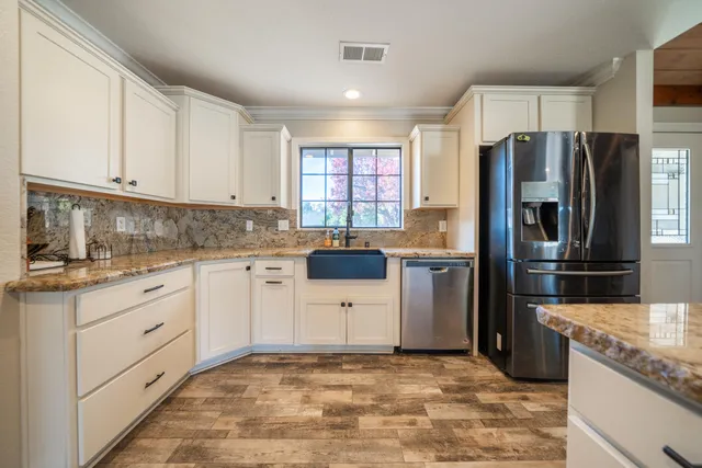 a kitchen with granite countertop a refrigerator sink stove and oven