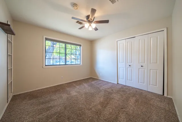an empty room with windows and fan