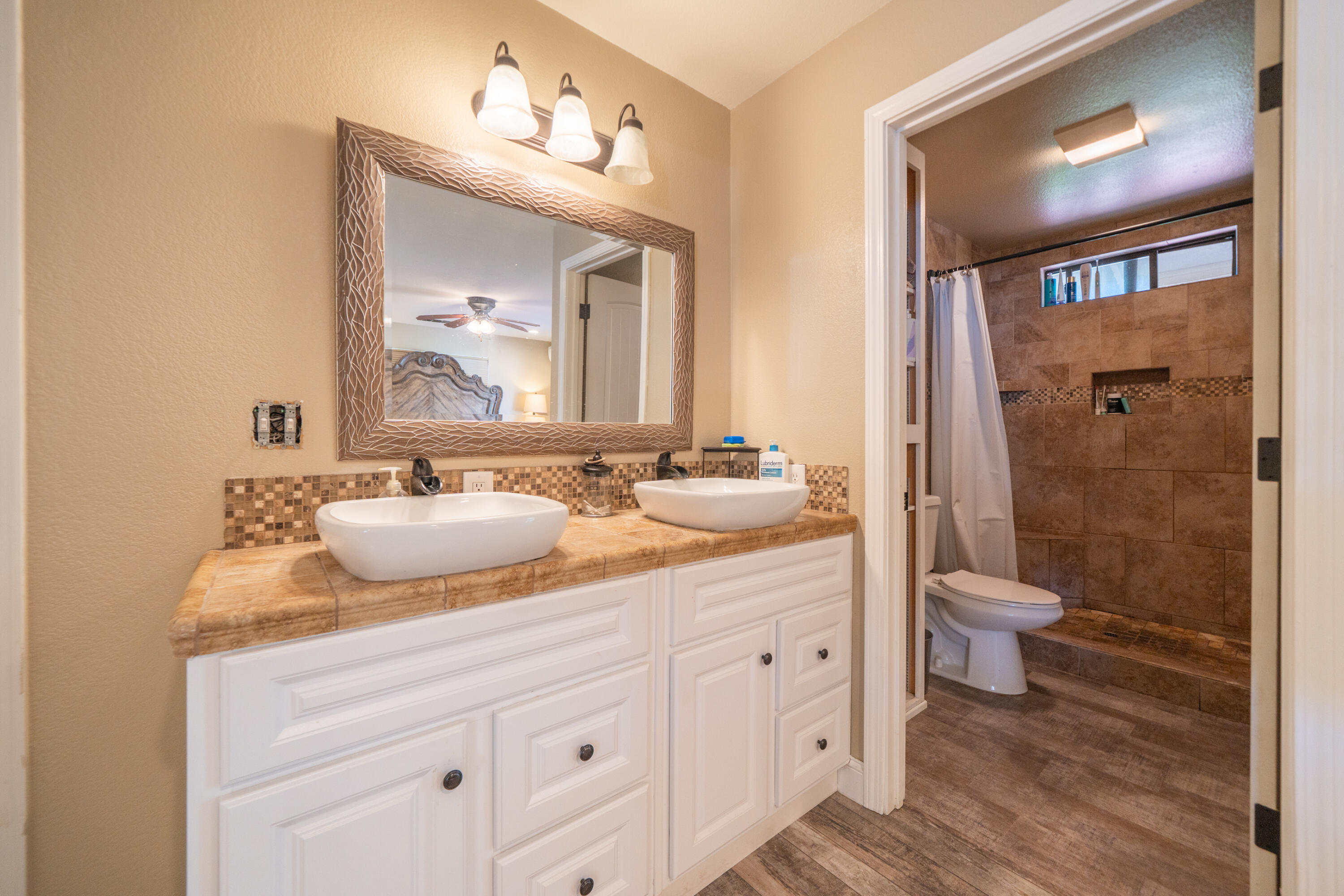 7273 Amigo Way Redding, CA 96002 - Photo 32 of 59 a bathroom with a granite countertop sink toilet a mirror and shower
