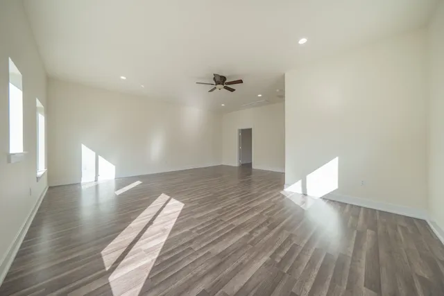 a view of an empty room with window and wooden floor