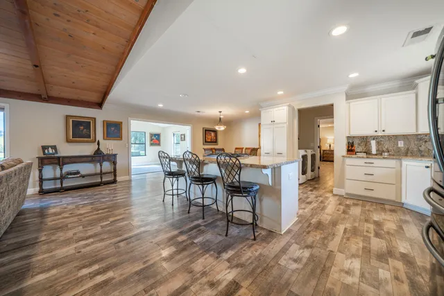 a living room with furniture and kitchen view with wooden floor