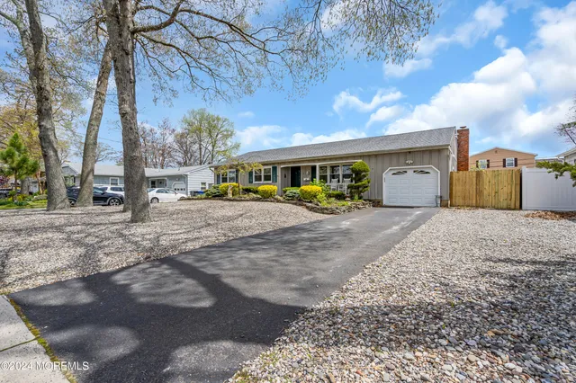 a view of a white house with a big yard and large trees
