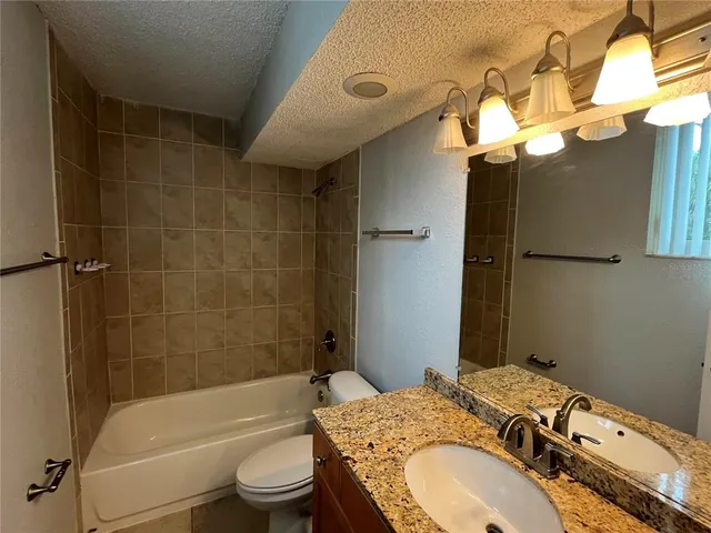a bathroom with a granite countertop sink a toilet and bathtub