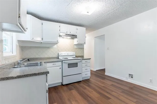 a kitchen with granite countertop a stove a sink and a window