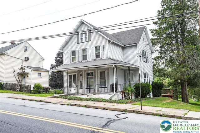 a view of a white house with a small yard and plants