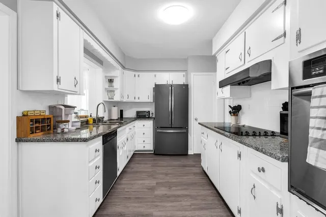 a kitchen with stainless steel appliances granite countertop a sink stove refrigerator and cabinets
