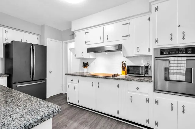 a kitchen with granite countertop white cabinets and stainless steel appliances