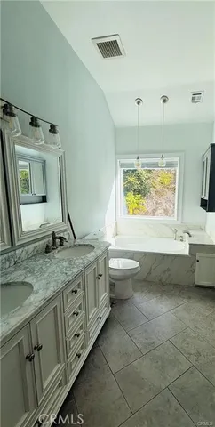 a bathroom with a granite countertop sink a toilet and mirror