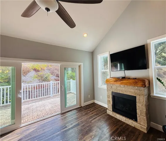 a view of an empty room with wooden floor fireplace and a window