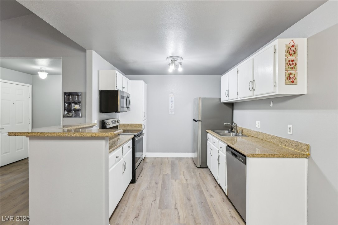 5241 South Lindell Road, Unit 202 Las Vegas, NV 89118 - Photo 13 of 35 Kitchen with light wood-style floors, appliances with stainless steel finishes, white cabinets, and a sink