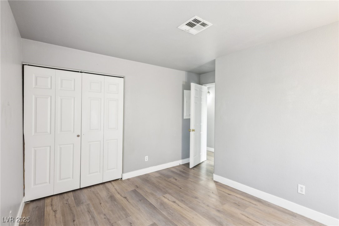 5241 South Lindell Road, Unit 202 Las Vegas, NV 89118 - Photo 21 of 35 Unfurnished bedroom featuring a closet, visible vents, baseboards, and wood finished floors