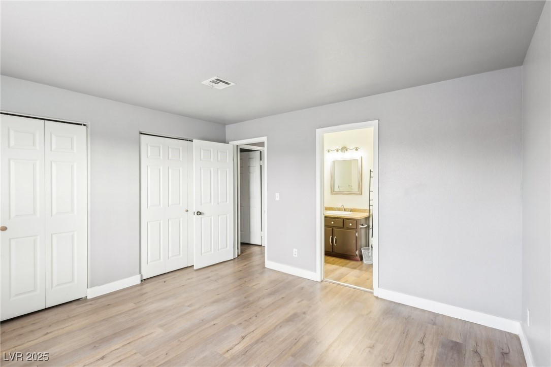 5241 South Lindell Road, Unit 202 Las Vegas, NV 89118 - Photo 26 of 35 Unfurnished bedroom with light wood-style flooring, a sink, visible vents, baseboards, and two closets