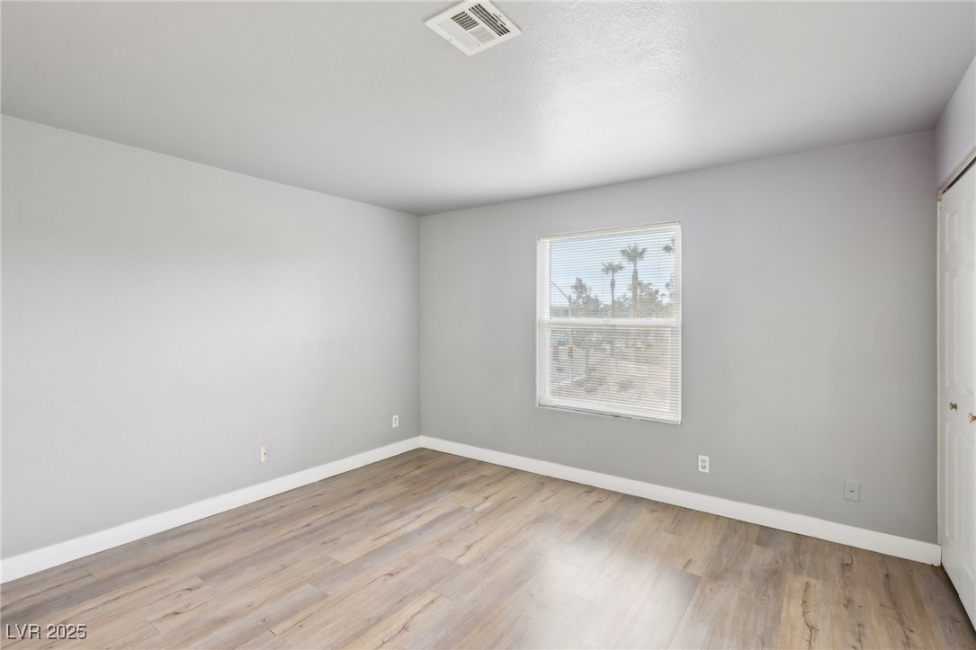 5241 South Lindell Road, Unit 202 Las Vegas, NV 89118 - Photo 28 of 35 Empty room featuring wood finished floors, visible vents, and baseboards